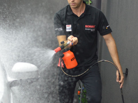 Profissional realizando a lavagem de um carro com Shampoo SONAX, aplicando o produto com técnica adequada para limpeza segura e acabamento premium.