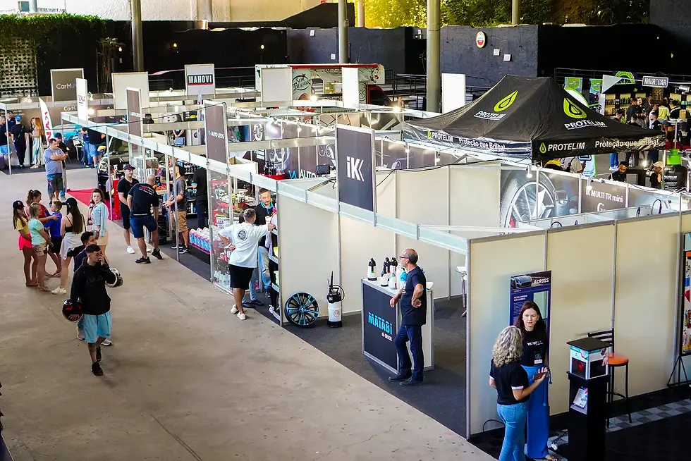 Feira de estética de carros Speedway com estandes e tendas de marcas, pessoas circulando e conversando em ambiente coberto e movimentado.