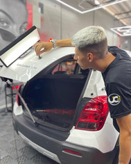 Um profissional da estética automotiva realizando uma verificação na lataria de um carro