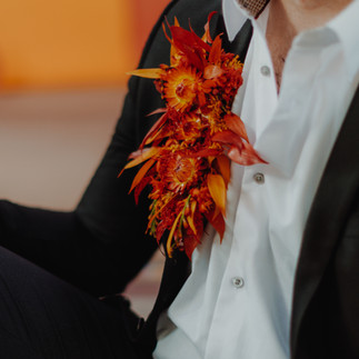 Black and white suit, with large firey button hole, with reds, yellows and oranages