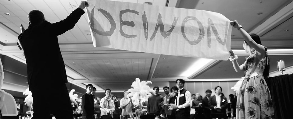 Corporate Vancouver Magician and Mentalist Bro Gilbert on stage with giant banner at corporate event