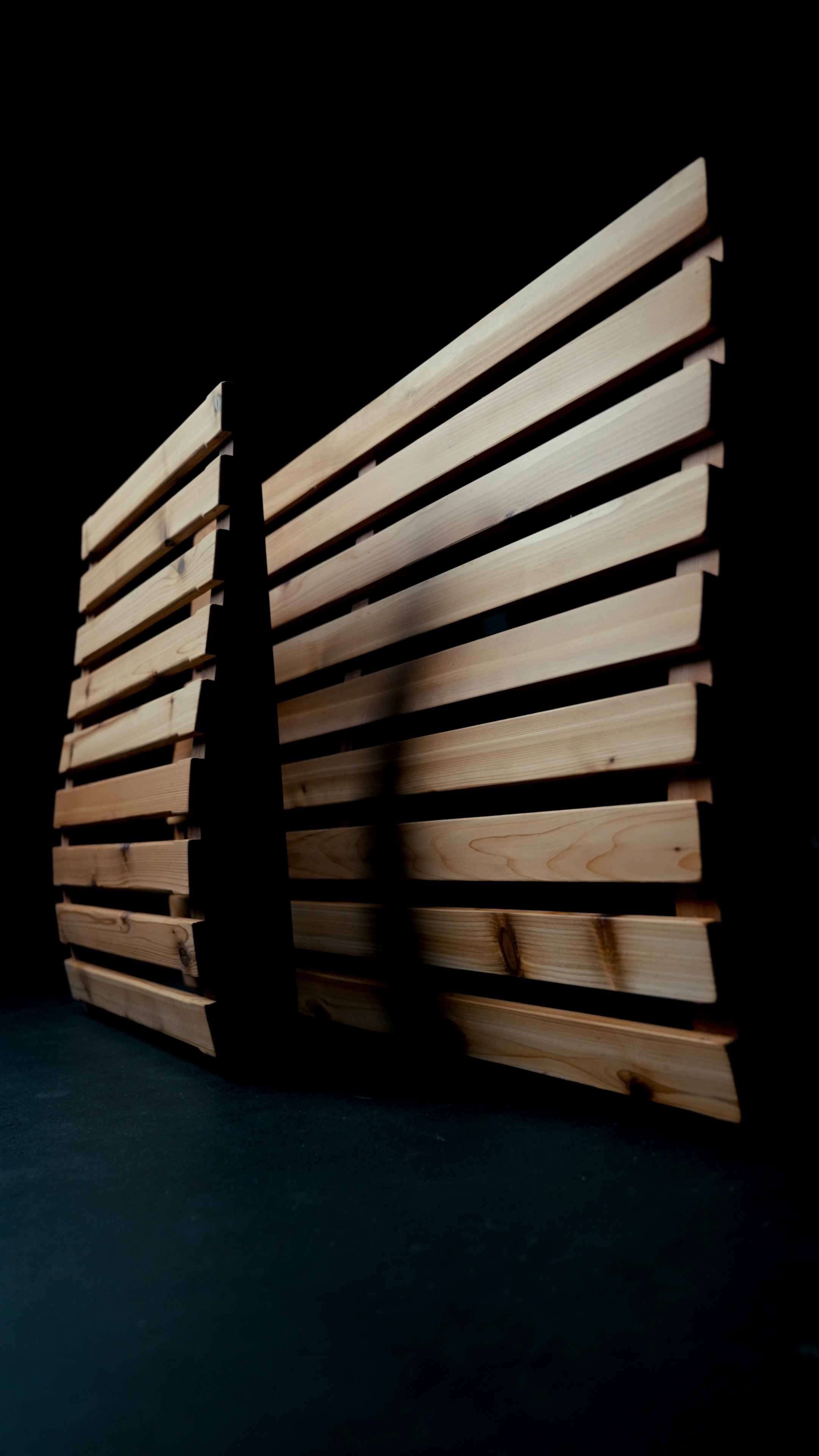 Flat wood wall panels from a Hot Box Sauna standing on edge against a dark background