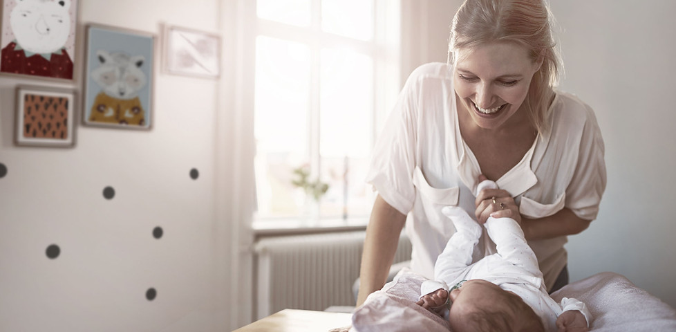 Mutter wickelt Baby auf einer Wickelauflage