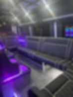 Purple lighting with black seats inside party bus
