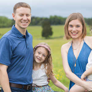 a family posing for a picture in a field with trees in the background