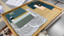 Interior design sample board created during the Bristol Folk House interiors course. A wooden tray displays fabric swatches, paint chips, and material samples curated for a home design scheme.