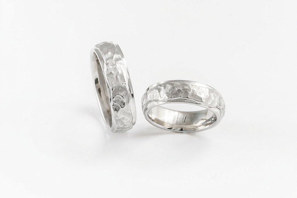 Packshot photography of two textured white gold rings with a hammered finish. The jewelry is presented on a clean, neutral background.