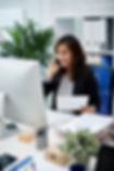 Asian business lady sitting in office, holding document and talking on mobile phone _ Free
