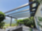 Moderne Terrassenüberdachung aus Glas mit dunklen Balken