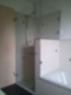 Moderne Glasdusche neben einer weißen Badewanne.