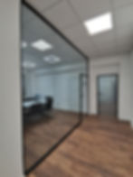 Transparente Ganzglaswand in modernem Büro mit Holzboden.