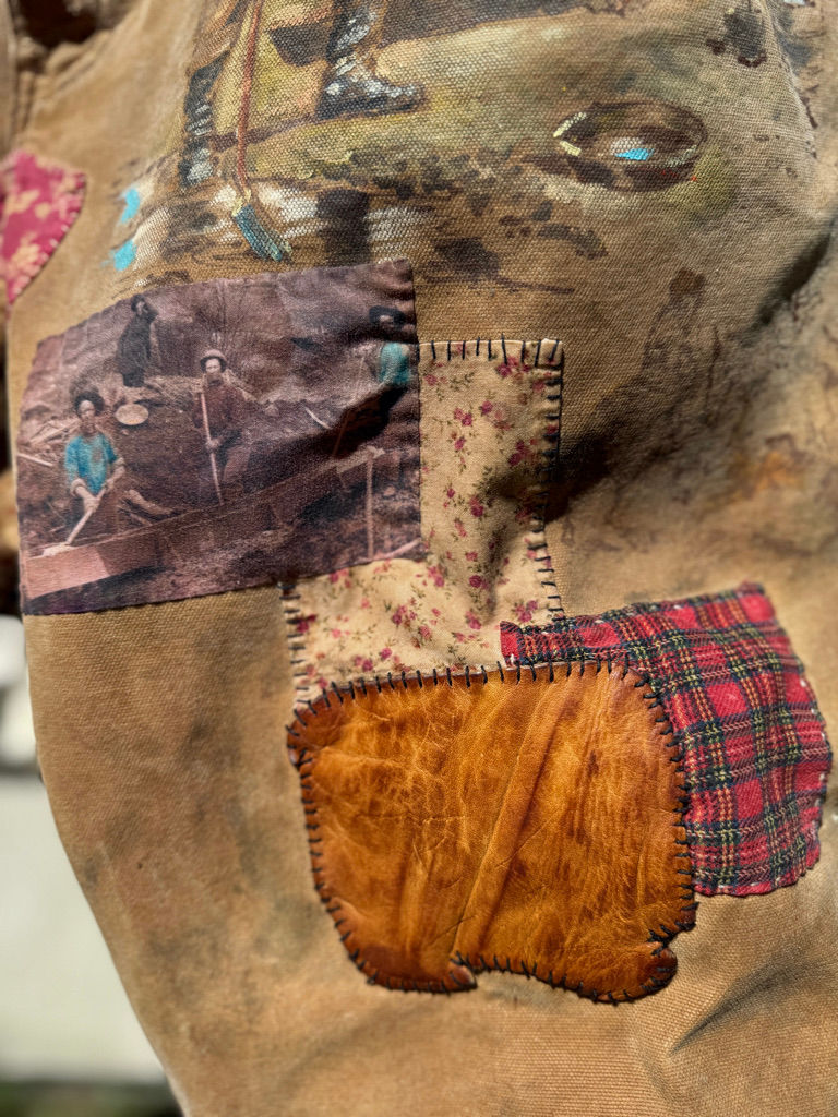 Thumbnail: Close-up of hand-stitched leather patch on vintage waxed canvas pants with visible texture and wear