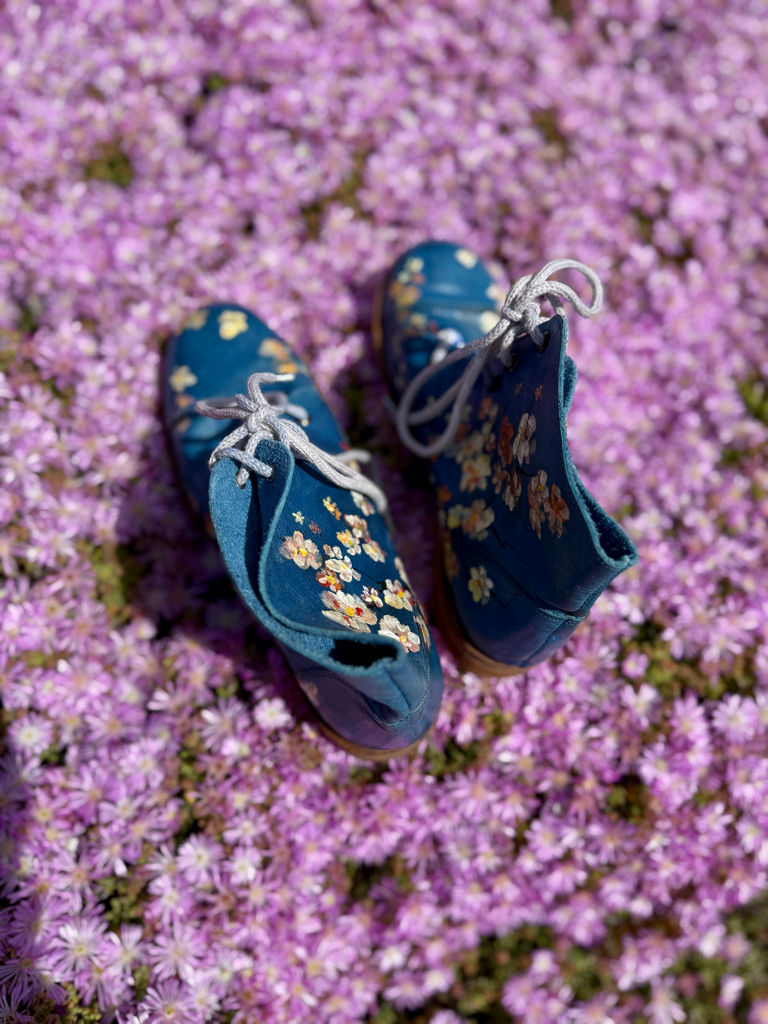 Thumbnail: Ocean Blossom floral leather boots photographed outdoors among vibrant spring flowers