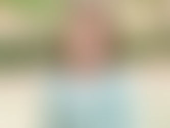 A white, 20-something woman with light brown hair posing for a headshot in front of a background of trees.