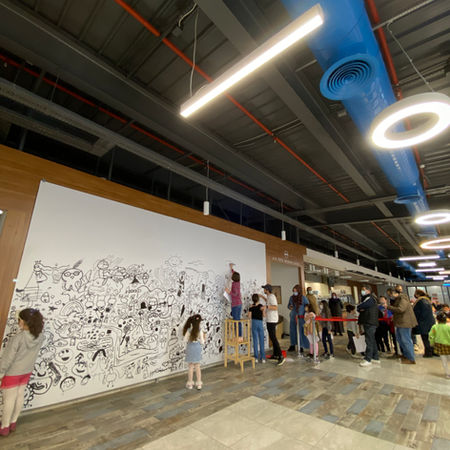 Küntay Tarık Evren posing with kids and their painted canvases at Ekol Lojistik headquarters.