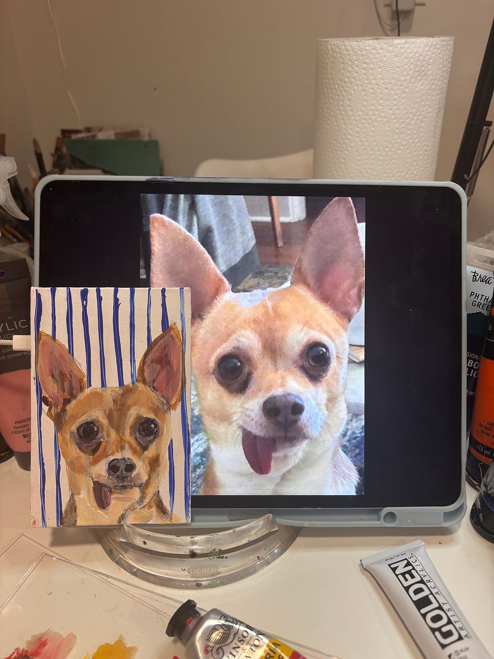 Close-up view of an artist’s hand painting a colorful cat portrait on canvas