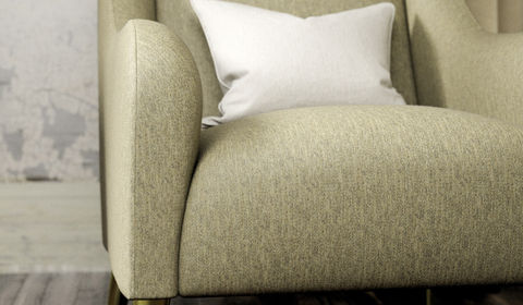 Close-up of a green armchair with a white pillow, showcasing the fabric texture.