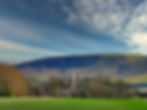 Church nestled in valley, under dramatic sky