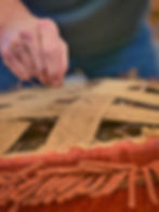 Hand threading a needle through burlap webbing for furniture upholstery