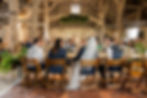 Bride and groom seated at wedding reception in rustic barn