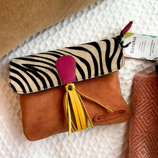 "A triptych of Soruka crossbody bags (pink/leopard, brown/zebra, blue/leopard) on flat-lay display with colourful blankets."
