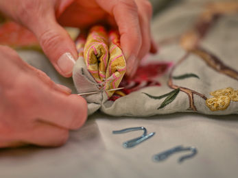 Hands sewing pleated fabric; curtain making
