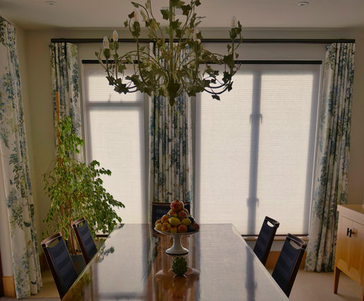 Elegant dining room with glass table, curtains, and chandelier