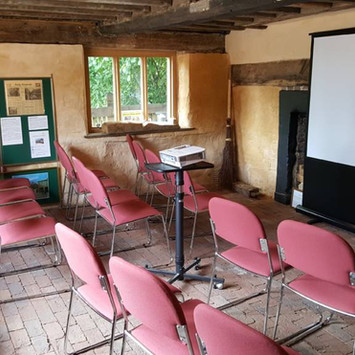 Room with chairs, projector screen, and historical photos