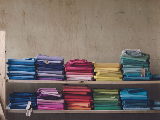 Stacked fabric swatches in various colors on wooden shelves