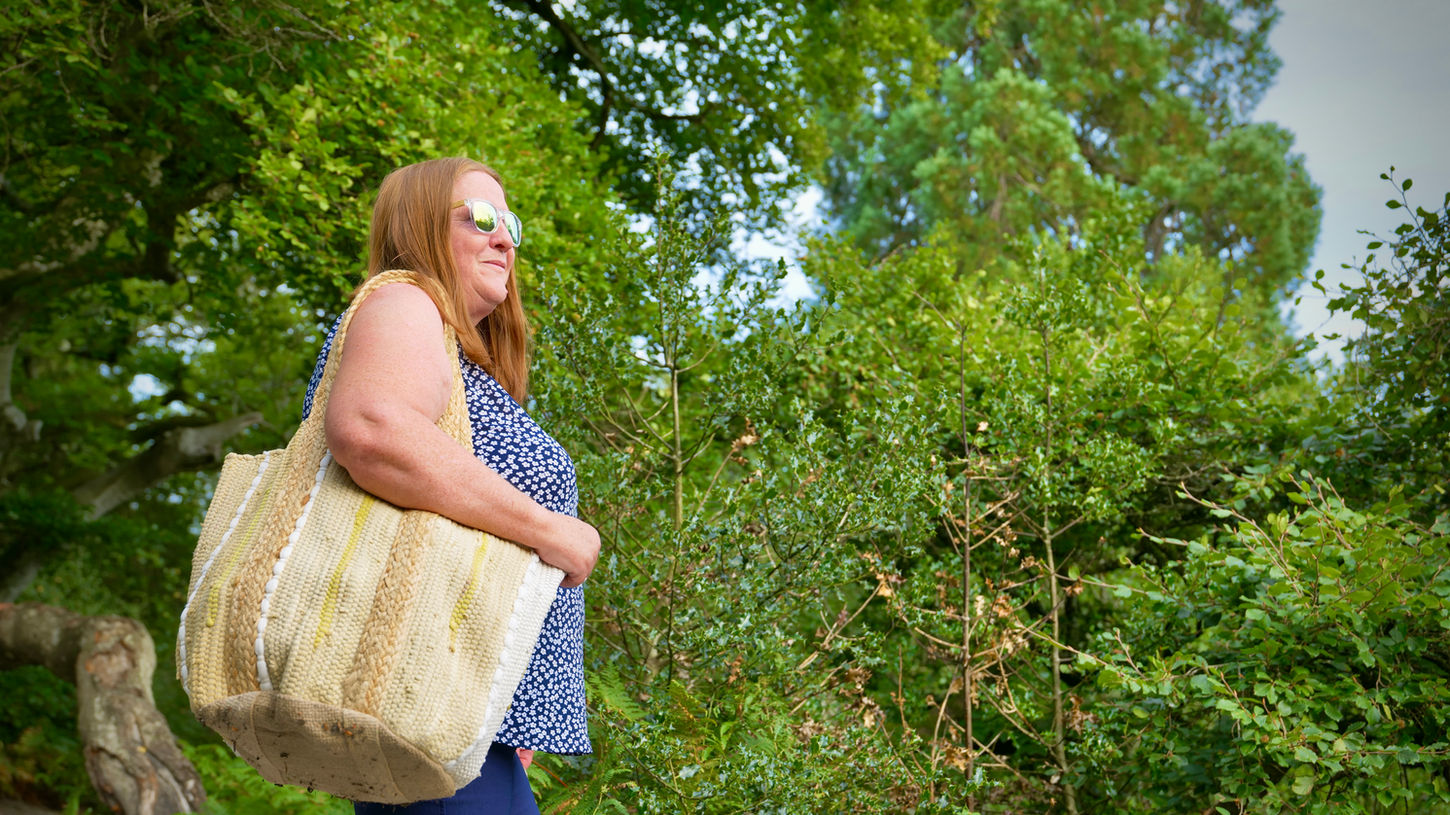 Woman outdoors carrying a large beige woven tote bag