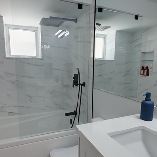 Large custom granite shower in a modern white contemporary bathroom in Oakville Ontario featuring black fixtures