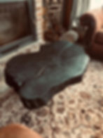 Mesa de centro rústica de madera oscura, en sala con alfombra y chimenea.