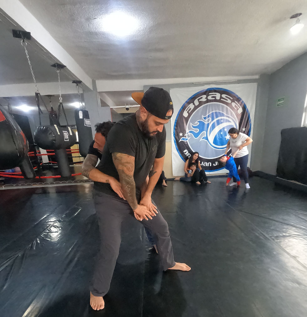Instructor Jonathan mostrando como defenderse de un agarre por la espalda en curso de defensa personal.