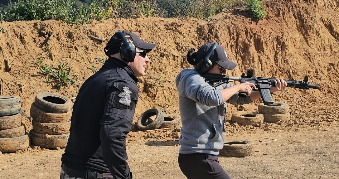 El instructor de tiro Erick Soto guiando a mujer en galeria de tiro