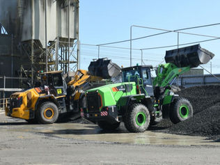 Entreprenadmaskiner i arbete på byggarbetsplats där både el- och dieseldrivna maskiner används för materialhantering.