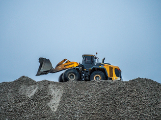 Gul LiuGong-hjullastare arbetar på grushög under blå himmel.