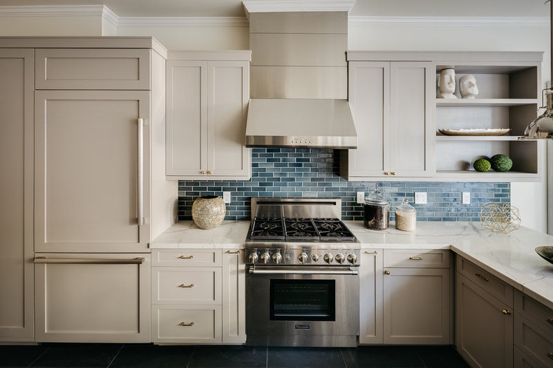 alt="Custom gray shaker kitchen with integrated panel refrigerator, stainless steel range and hood, white quartz countertops, and blue tile backsplash, designed and installed by Knoxville Custom Homes"