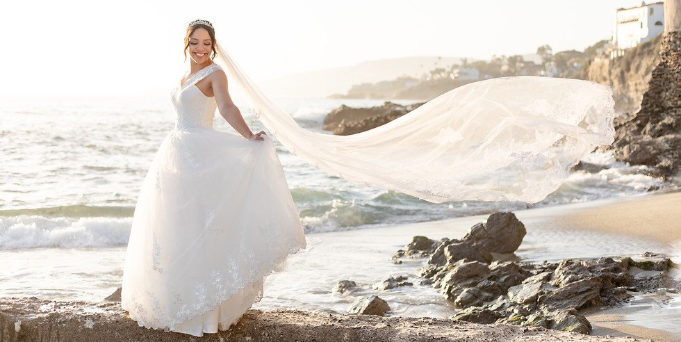 Image of a bride posing on a beach with her veil blowing in the wind