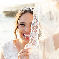 Image of a bride holding up her veil to cover half her face