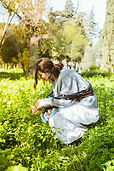 Woman kneeling in grass mindfully engaging with plants outdoors