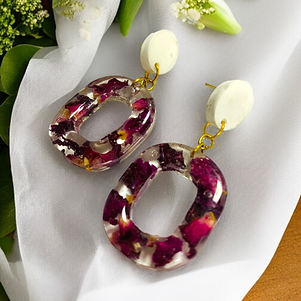 The earrings are transparent and encase a dense mix of dried rose petals,and attached to a light white stud.