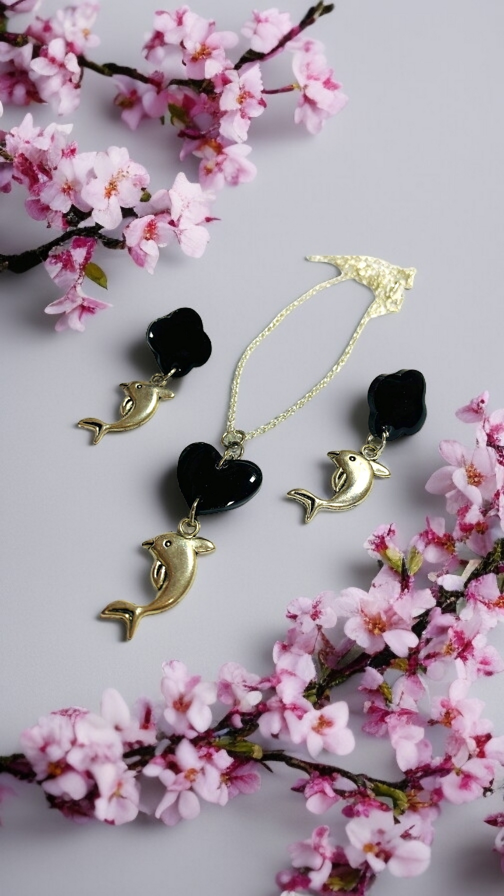 The set includes a necklace and a pair of earrings silver chain with a black heart  pendant with silver dolphins