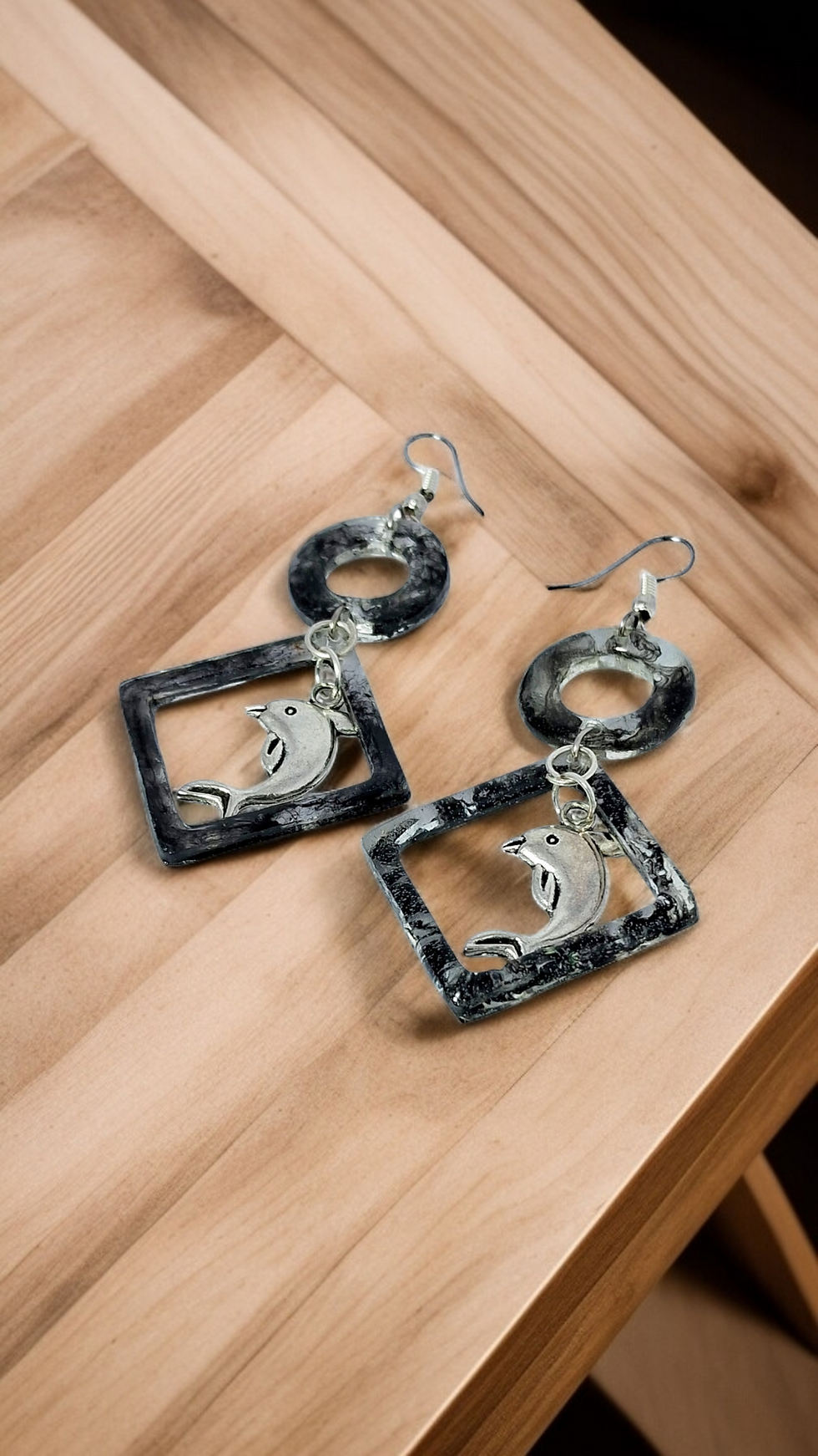 Handmade ocean-themed jewelry: two unique geometric earrings with a playful dolphin design.