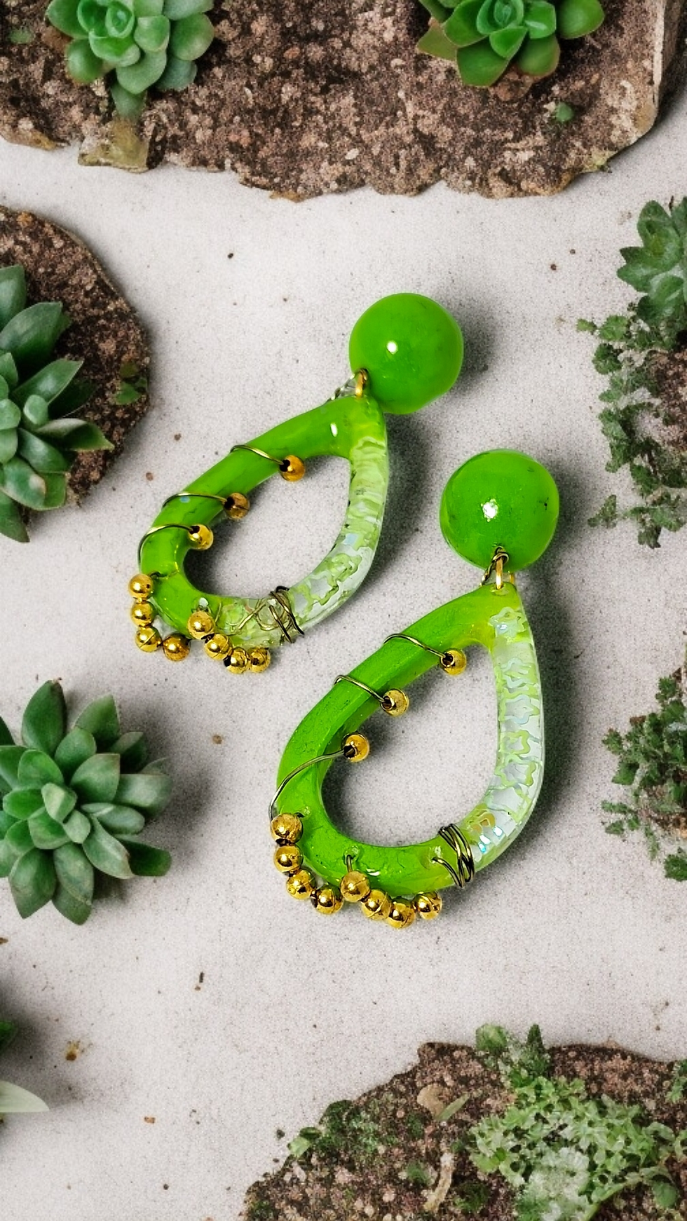 Close-up of unique statement dangle earrings crafted from lime green resin, featuring delicate flower sequins, a golden pearl