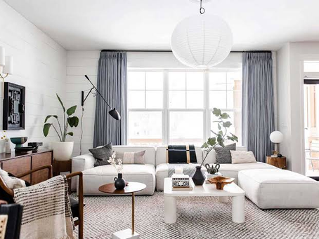 Living room layout balancing a low-profile grounded sofa with leggy wooden accent chairs and an open metal side table