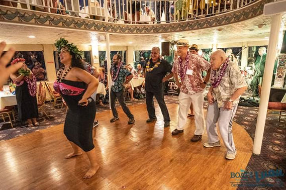 Attendees dancing in sync with a captivating hula dancer, embracing the rhythm and spirit of Hawaiian culture, creating a vibrant and memorable experience for all.