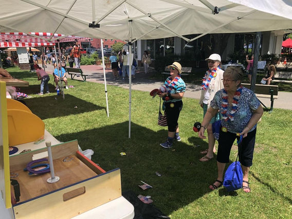Guests playing the Hoop Shot Ring Toss carnival game operated by Magical Memories Entertainment at an outdoor event.