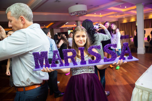 Girl holding a glitter sign with her name during a Bat Mitzvah celebration.