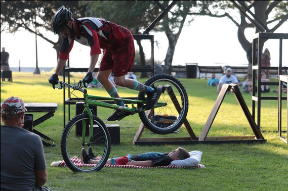 A bike trickster performing daring stunts and impressive maneuvers on a BMX or mountain bike at an event. Spectators watch in awe as the rider jumps, flips, and twists through the air, demonstrating skill and precision. The thrilling performance adds an exciting and adrenaline-pumping element to the event, leaving the audience amazed and entertained.