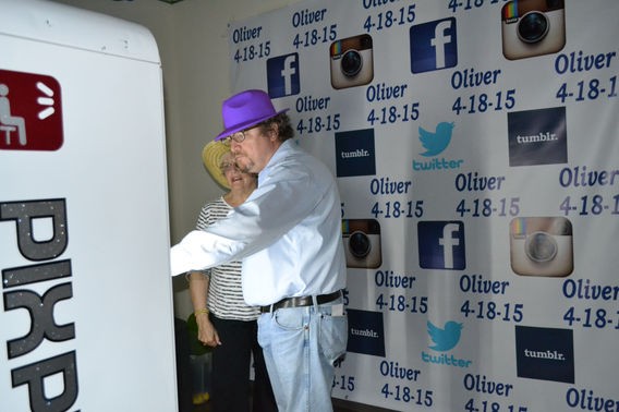 Guest posing at giant selfie machine with branded backdrop